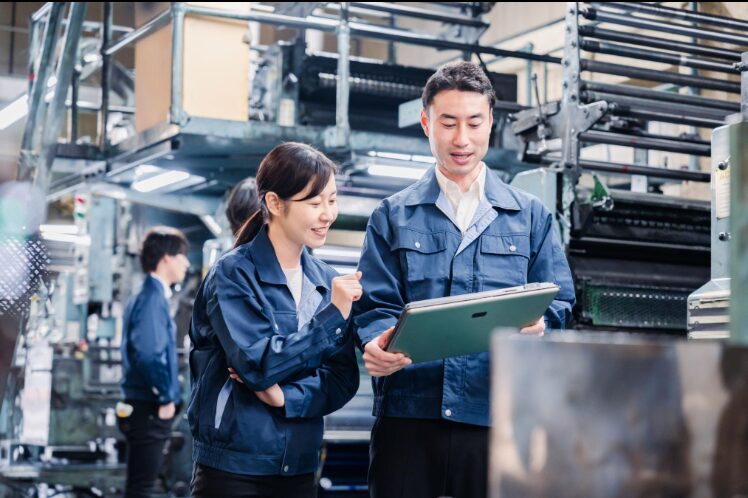 2 people in blue jackets looking at a tablet